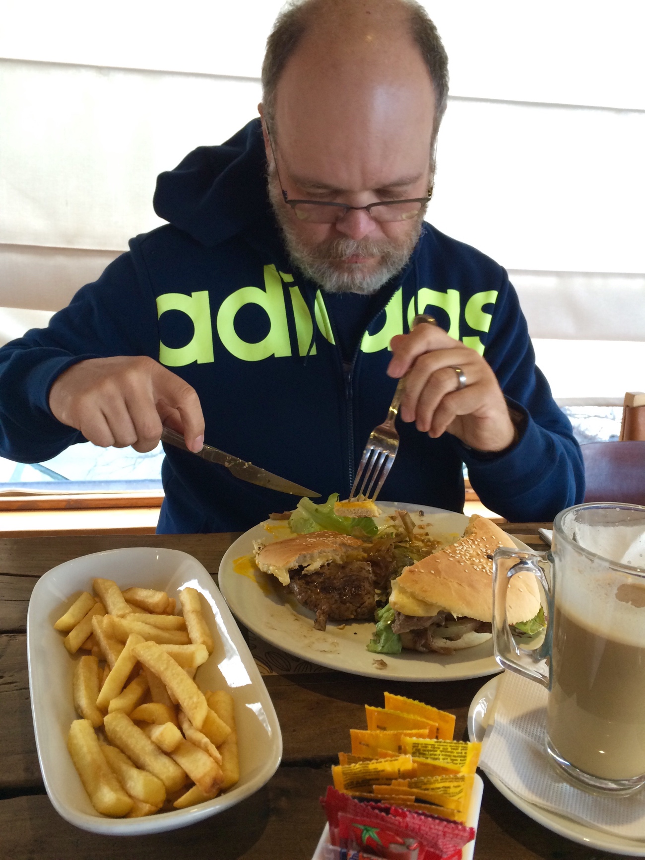 Glenn eating a hamburger with a knife and fork