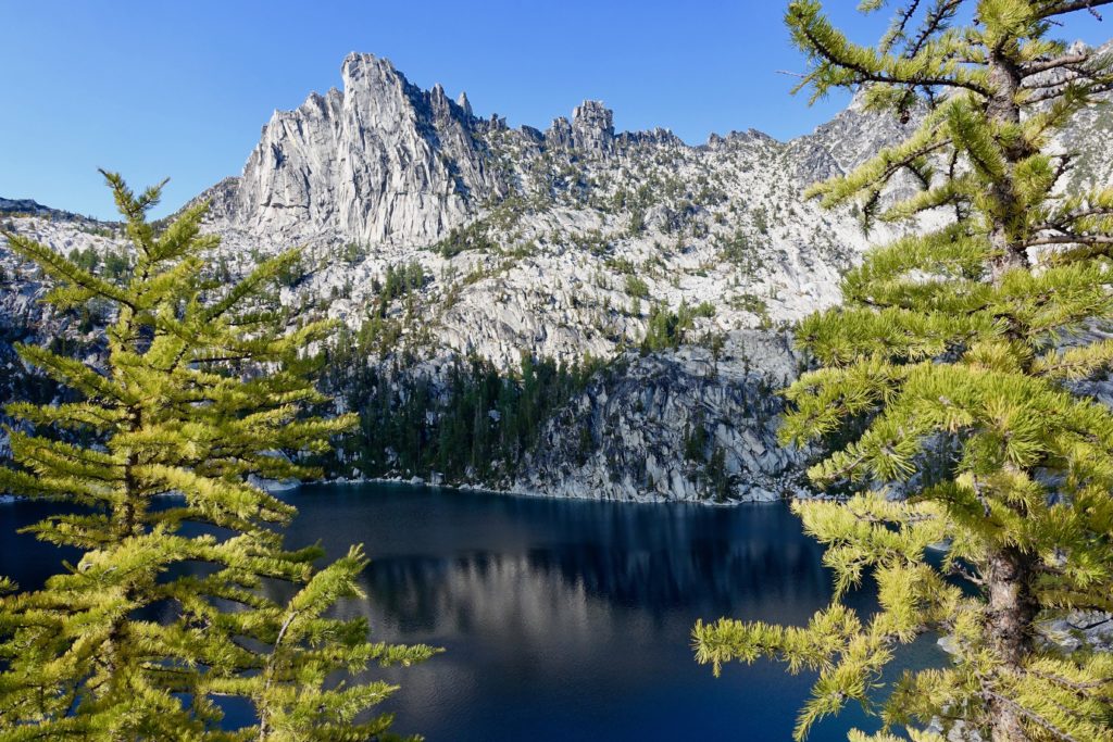 Beautiful view with the contrast of the blue skies, gray rocks, indigo water and yellowing pine trees.