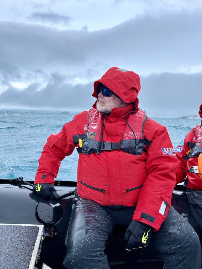 Glenn sitting in the front of the zodiac on a windy day.